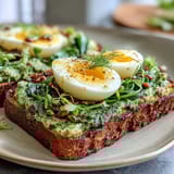Vibrant spinach pesto sourdough toast topped with a perfectly soft-boiled egg and garnished with chili flakes.