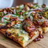 Savory BBQ chicken flatbread pizza topped with red onion, bell pepper, and a drizzle of tangy sauce.  