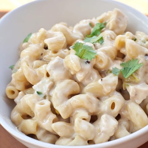 Creamy Green Chili Chicken Mac with shredded chicken and melted Monterey Jack cheese in a skillet.  