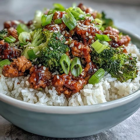 A close-up view of a wholesome dinner bowl featuring tender turkey, minced garlic, ginger, and a garnish of sesame seeds and green onions.