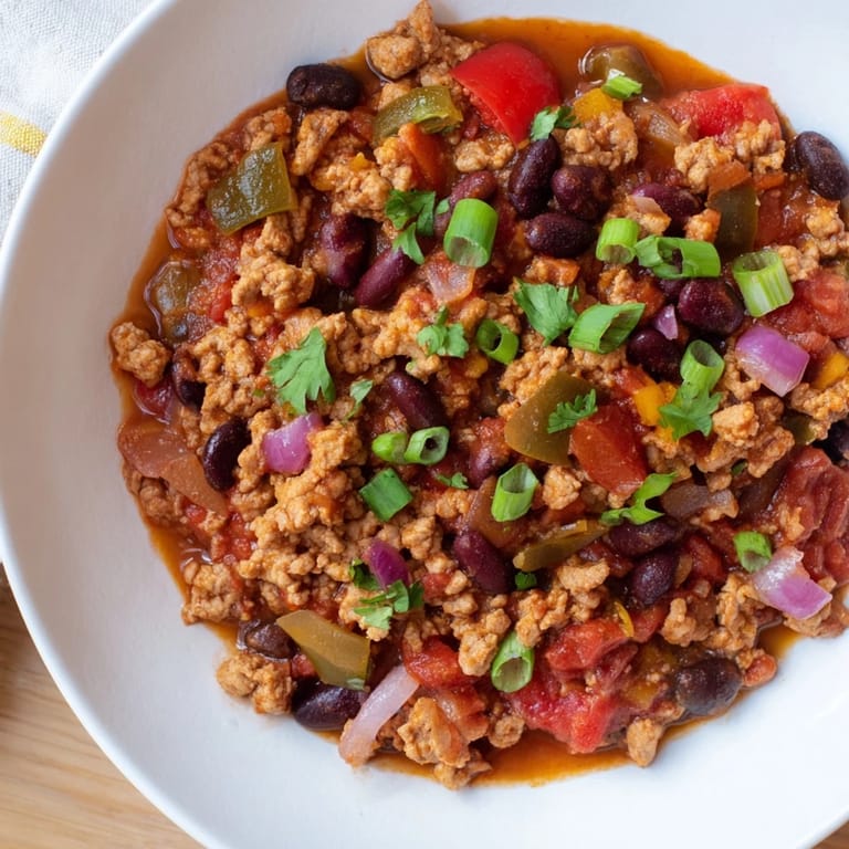Close-up of a flavorful turkey chili with visible beans, spices, and diced vegetables for dinner.