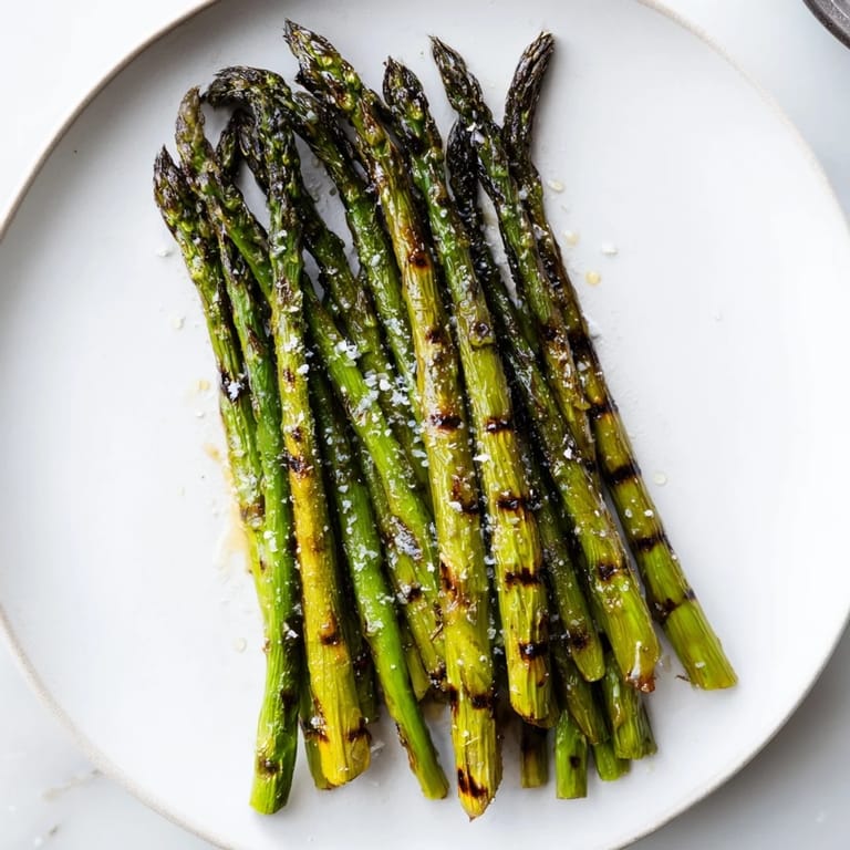 Enjoy this vibrant photo of perfectly grilled asparagus, glistening with olive oil and seasoned to perfection.