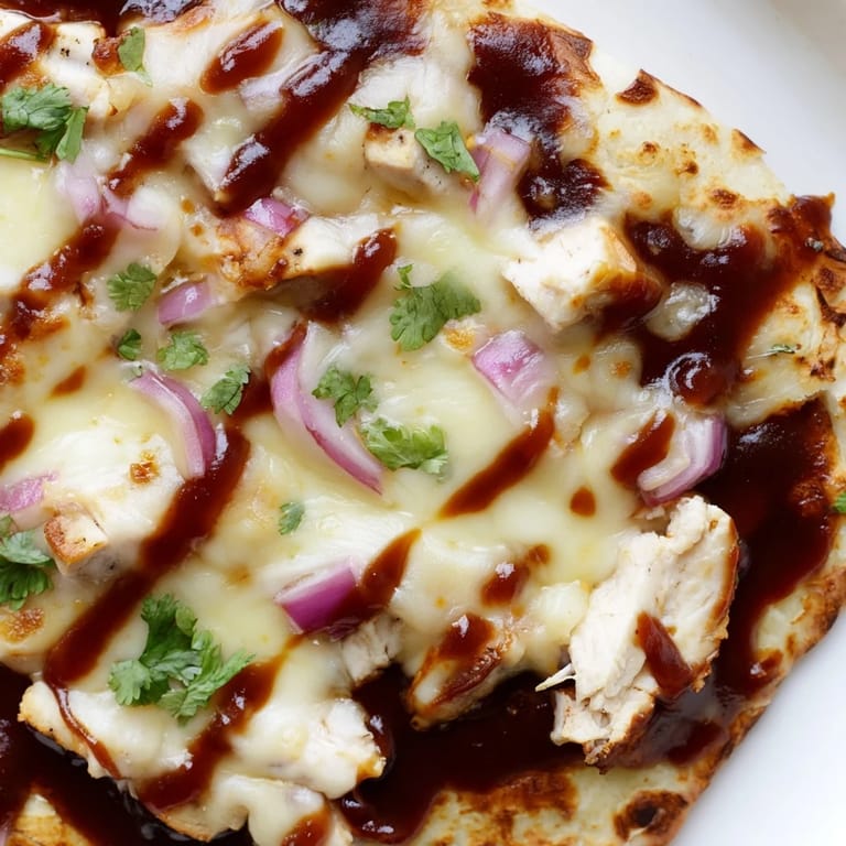 Sliced BBQ Chicken Flatbread pieces served on a wooden board with extra drizzled barbecue sauce.