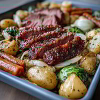 A hearty sheet pan dinner of corned beef and cabbage with roasted potatoes and carrots, golden and caramelized.  
