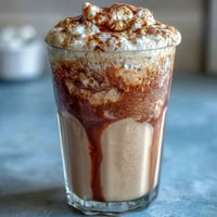 Creamy vanilla bean frappuccino protein shake with real vanilla and ice, topped with whipped cream in a tall glass.