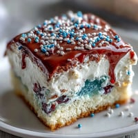 Vibrant Patriotic Poke Cake with glossy white chocolate ganache, ready for celebration.